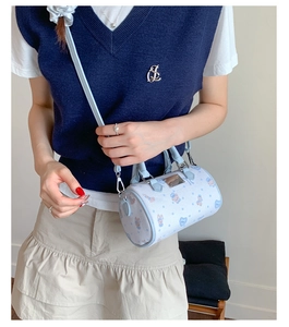 Detail of light blue cylinder bag with cute cartoon bear and rabbit prints and metal plate