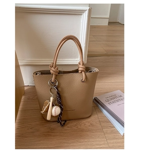 Detail of light brown lychee leather bucket bag with creative baseball charm set