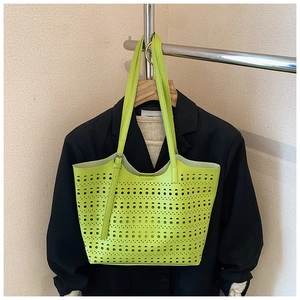 Détail du sac cabas évidé vert fluo avec motifs découpés au laser et fines anses de transport