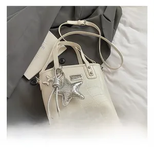 Detail shot of the crocodile embossed texture and star charms on the cream bucket bag