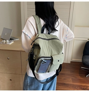 Detailed view of an olive green travel backpack with transparent front pocket and nylon texture