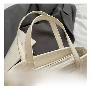 Detail of off-white crocodile texture handbag with silver studs and sturdy handles