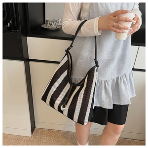 Detail of striped woven hobo bag with slim leather strap and silver metal hardware