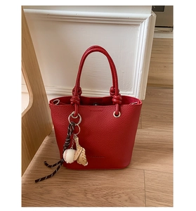 Close-up of red lychee textured bucket bag featuring baseball glove charm and fashion logo