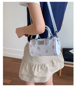 Detail of light blue cylinder boston bag featuring cute bear and bow prints with a metal logo
