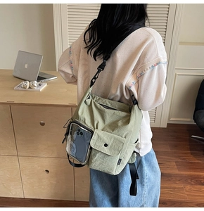 Detail view of light green nylon crossbody bag with transparent phone pocket and snap flap