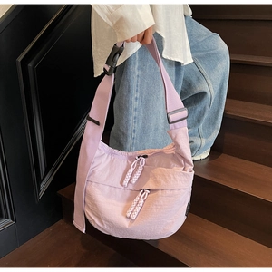 Detail of lavender nylon crossbody bag showing zippers and wide strap on stairs