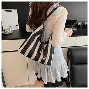 Detail of black and white striped woven tote bag with slim shoulder strap and metal ring