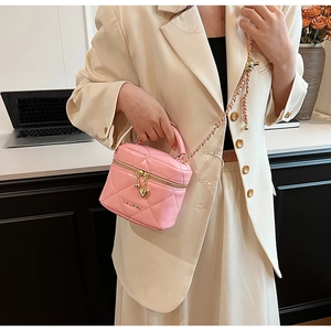 Mini borsa a secchiello trapuntata rosa con catena dorata su abito beige