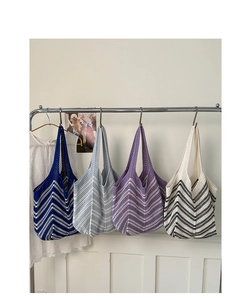 Dettaglio di quattro grandi borse tote in maglia a righe colorate appese alla rastrelliera