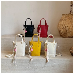 Détail de mini sacs seaux de couleurs variées avec breloques cœur sur des marches en pierre