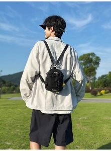 Detail view of a compact black nylon outdoor backpack with neon pendant and drawstring closure