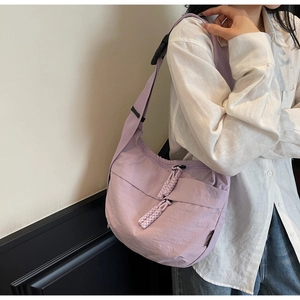 Detail of lavender nylon dumpling bag featuring decorative rope zipper pulls and buckle strap