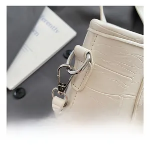 Close-up of high-quality silver metal hook and D-ring on beige crocodile pattern bag