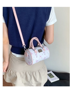 Detailed view of pink cartoon cylinder bag featuring rabbit prints and silver metal plaque