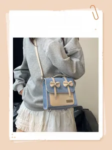 Detail view of denim crossbody bag with white leather trim and cute bow decorations