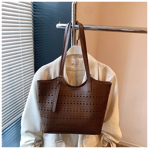 Détail de motifs géométriques découpés au laser sur un grand sac cabas marron
