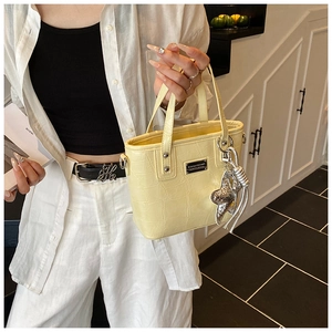 Detail of croc-embossed yellow mini tote bag with starfish charm and tassel accessory