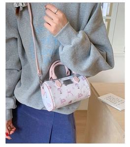 Detail of a mini cylinder crossbody bag with pink trim and cute cartoon puppy prints