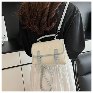 Detail of cream and blue crossbody bag with PAN TOR embossing and silver metal buckles