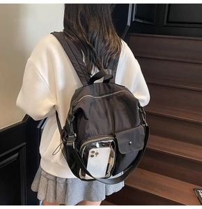 Detailed back view of a black nylon backpack with padded straps on wooden stairs