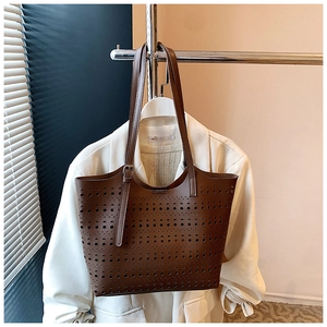 Détail du motif ajouré au laser et de la bandoulière réglable du sac cabas marron