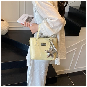 Detail of cream yellow crocodile embossed bucket bag with silver star charm and hardware