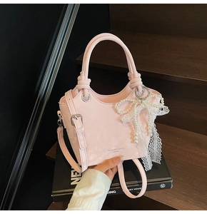Vue détaillée du sac seau rose avec décoration de nœud en perles et fermoirs métalliques