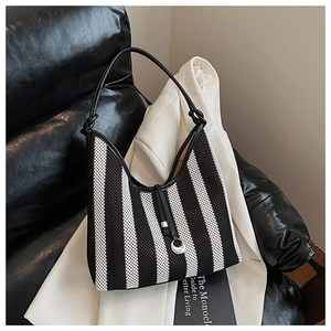 Detail of striped woven tote bag with leather handle and silver moon pendant accessory