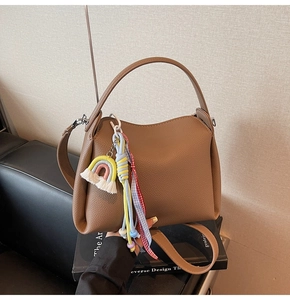 Détails du sac seau marron avec charm arc-en-ciel et ruban décoratif à carreaux rouges