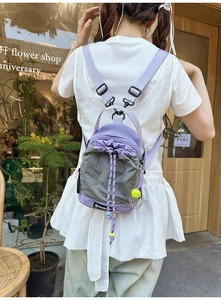 Detail of purple crossbody bag with drawstring closure and tennis racket charm pendant
