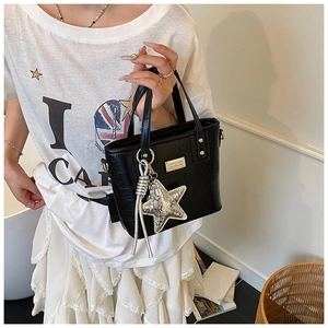 Detail of black croc-embossed handbag with silver star charm and metallic brand plaque