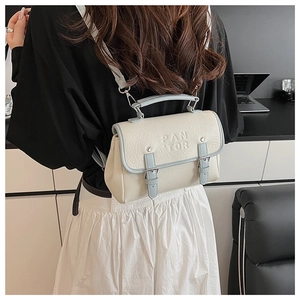 Detailed back view of a minimalist cream small square bag worn as a trendy backpack