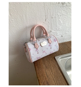 Detail of printed Boston handbag with cartoon motifs on a rustic wooden surface