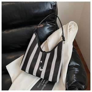 Detail of striped woven hobo bag featuring black shoulder strap with side knot accents