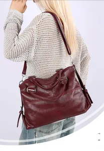 Side view of a burgundy leather tote bag with silver hardware on a model's shoulder