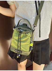 Detail of army green drawstring crossbody bag with textured fabric and tennis charm
