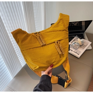 Detail of yellow nylon crossbody bag with braided zipper pull and wide shoulder strap