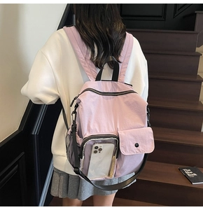 Detail of lavender nylon travel backpack featuring a transparent PVC phone pocket on a model
