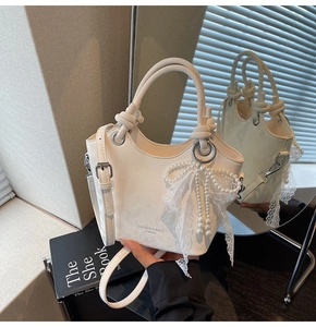 Détail du sac seau blanc crème avec pendentif nœud en dentelle et perles élégant
