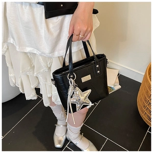 Close-up of black crocodile embossed bucket bag with silver star charm and metal brand plate