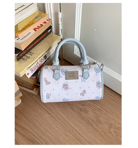 Detail of mini Boston bag with bear patterns and silver brand logo plate on wood floor