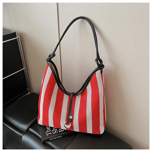 Detail of red and white striped knit hobo bag with knotted black handle and silver charm