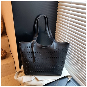 Détail des motifs perforés au laser et de la sangle à boucle d'un grand sac cabas noir