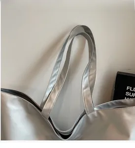 Close-up of durable double handles and fine stitching on the silver metallic tote bag