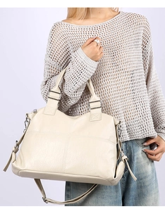 Detailed close-up of large off-white leather tote bag with cross stitching and silver hardware