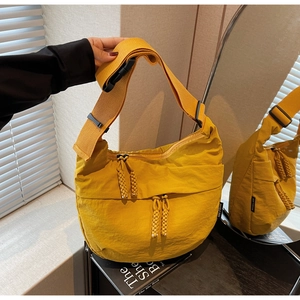Detail of yellow nylon crescent bag featuring adjustable wide strap and woven zip pulls