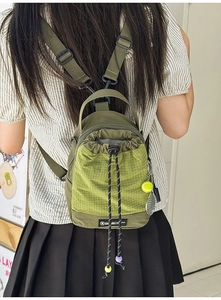 Close-up of military green drawstring bag with neon green mesh and tennis racket charm