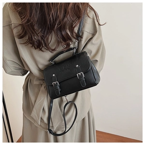 Detailed view of the black matte leather messenger bag with silver metal buckles and logo