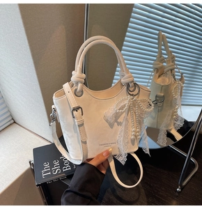 Détail d'un sac seau blanc avec breloque en perles et dentelle et anneau en métal